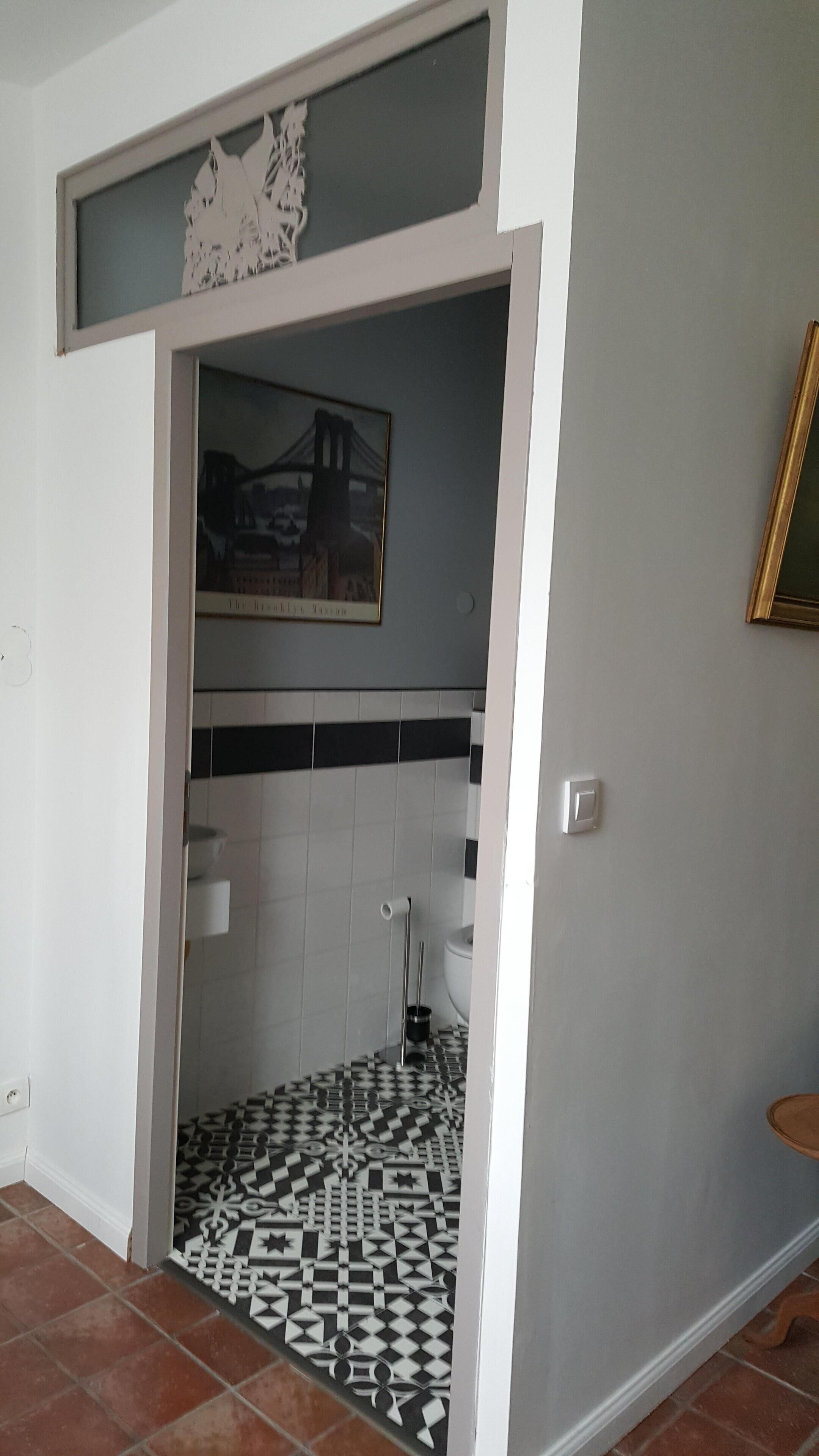A bathroom with a patterned floor, a toilet, a sink, and a shower.