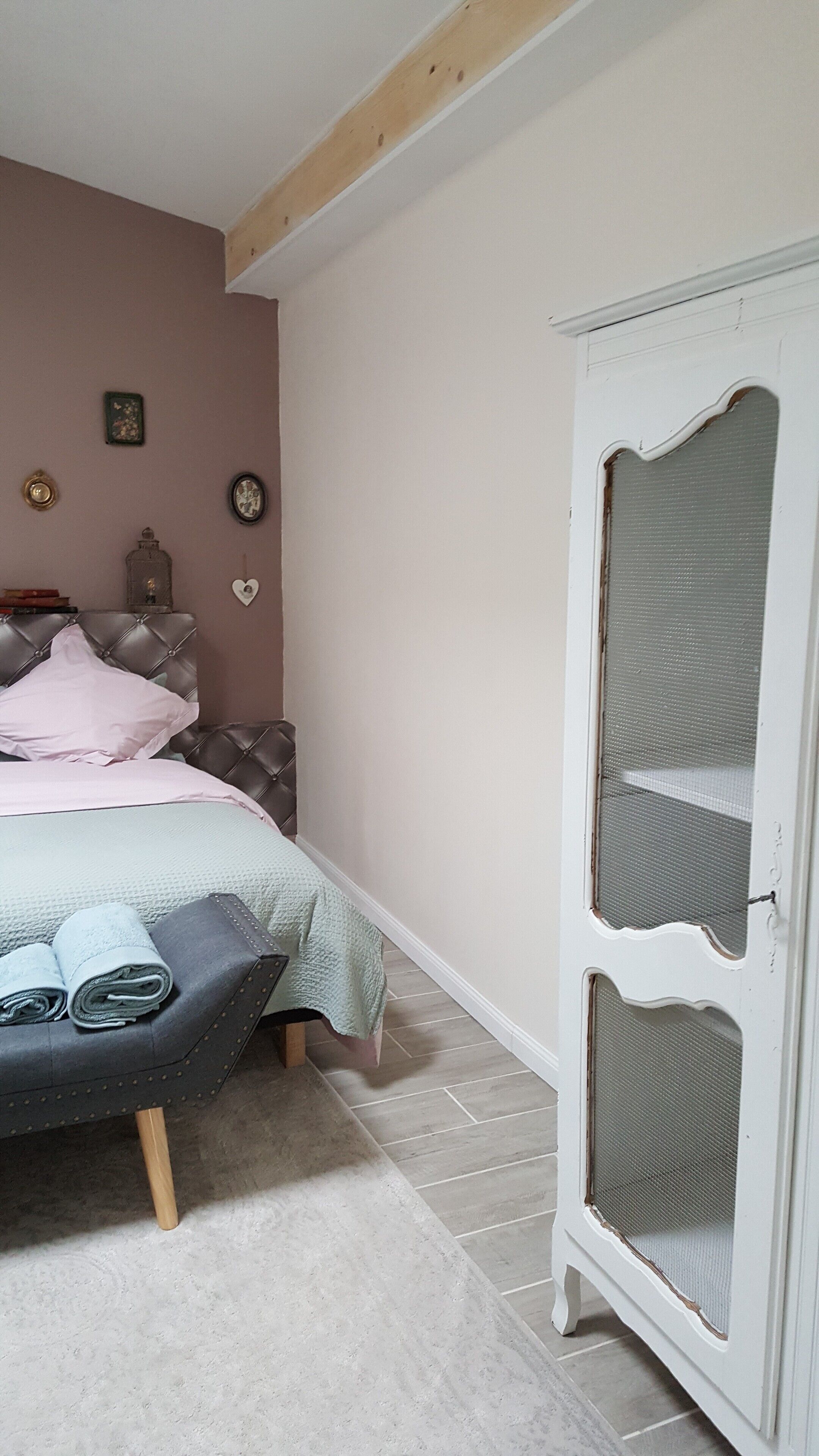 Een slaapkamer met een bed, een kledingkast en een wandklok.