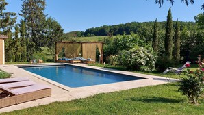 A rectangular swimming pool with lounge chairs and a pergola in a lush garden setting. - Grand cru house (Chardonnay)