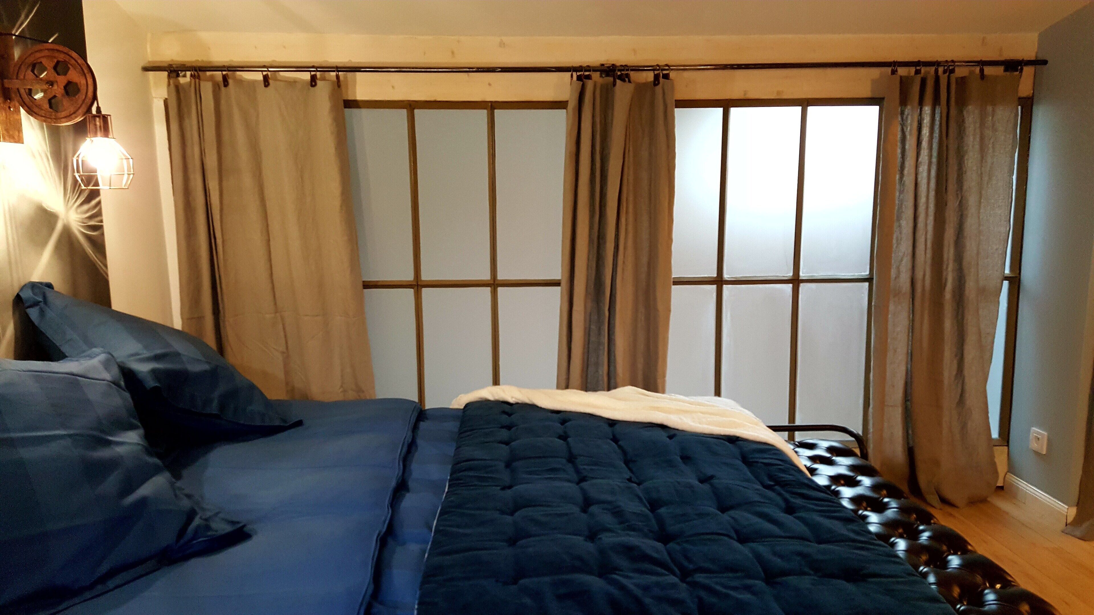 A bedroom with a bed, curtains, and a window.