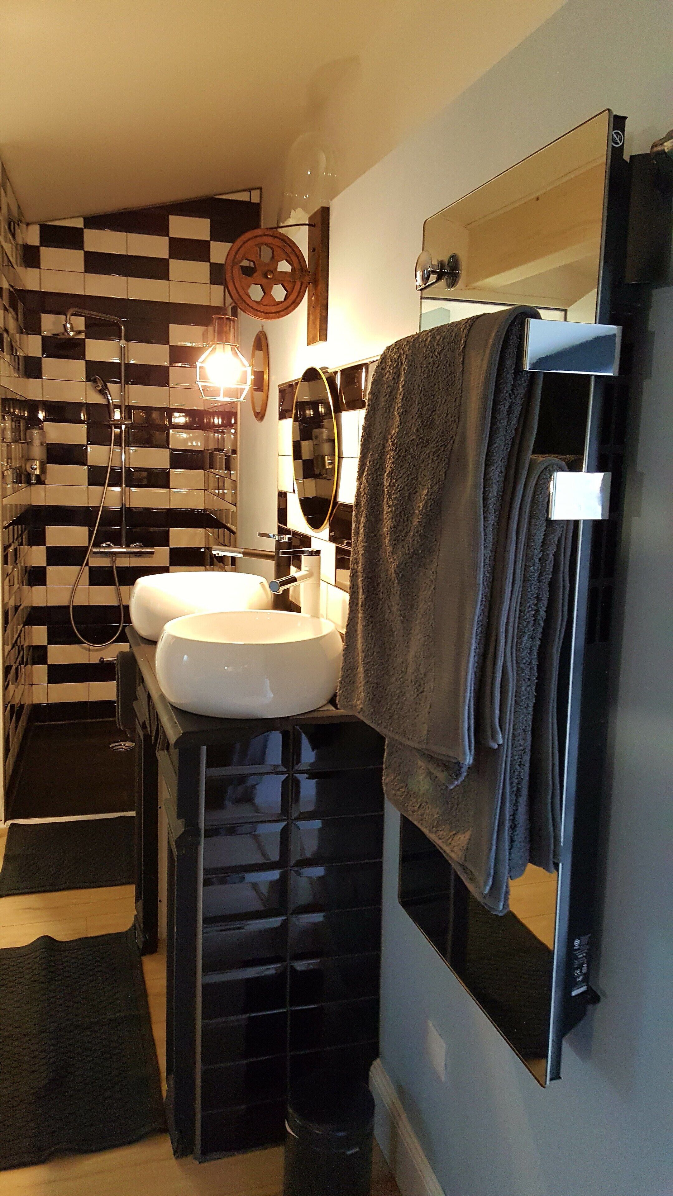 A bathroom with two sinks, a shower, and a towel rack.