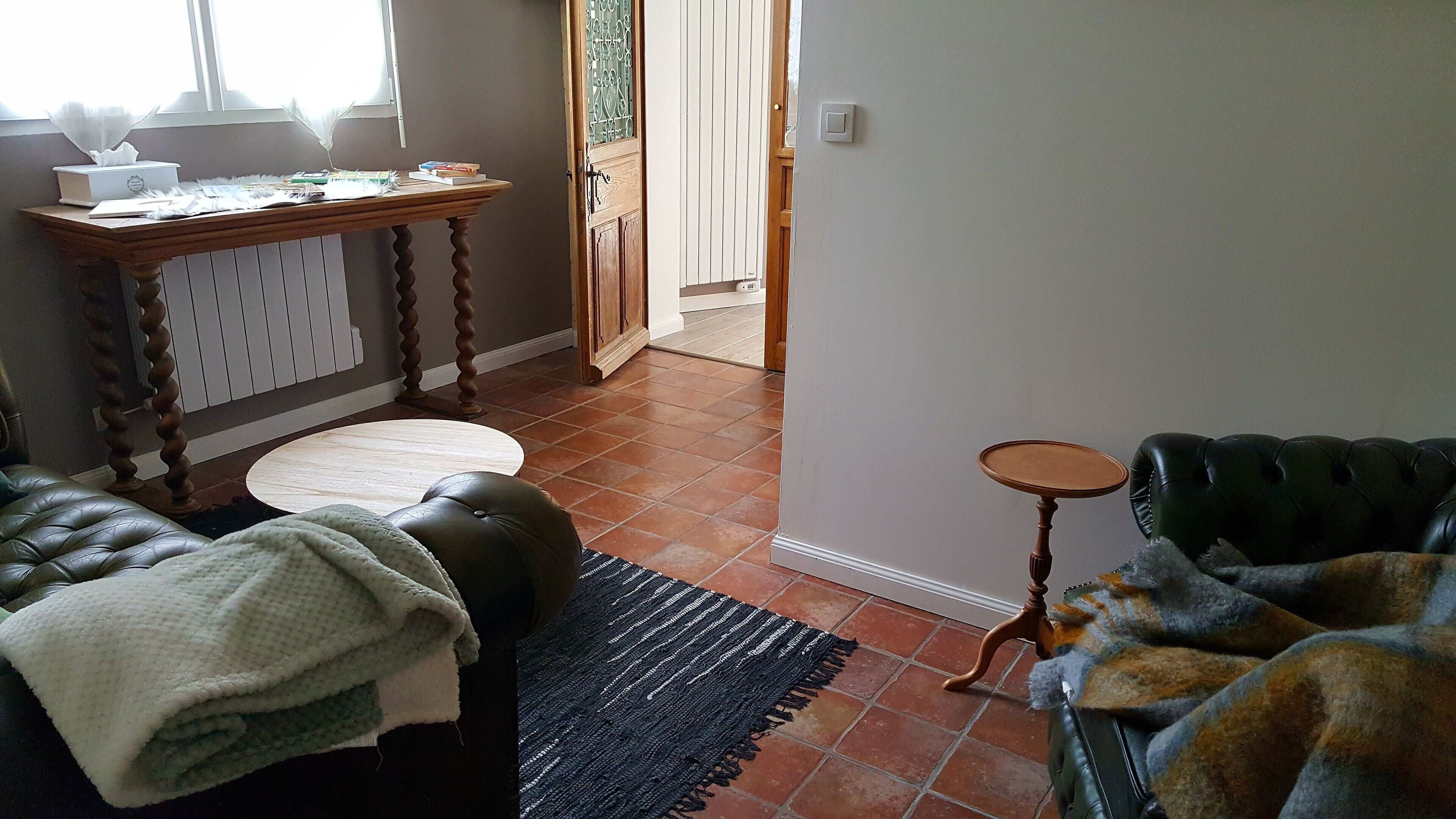 A living room with a leather sofa, a small round table, and a wooden table with books and a tissue box.