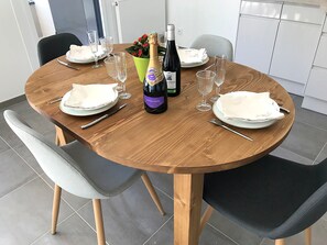 A round wooden dining table with white plates, cutlery, and two bottles of champagne. - T3 Golden Triangle : Annecy Green *** (ANNECY)