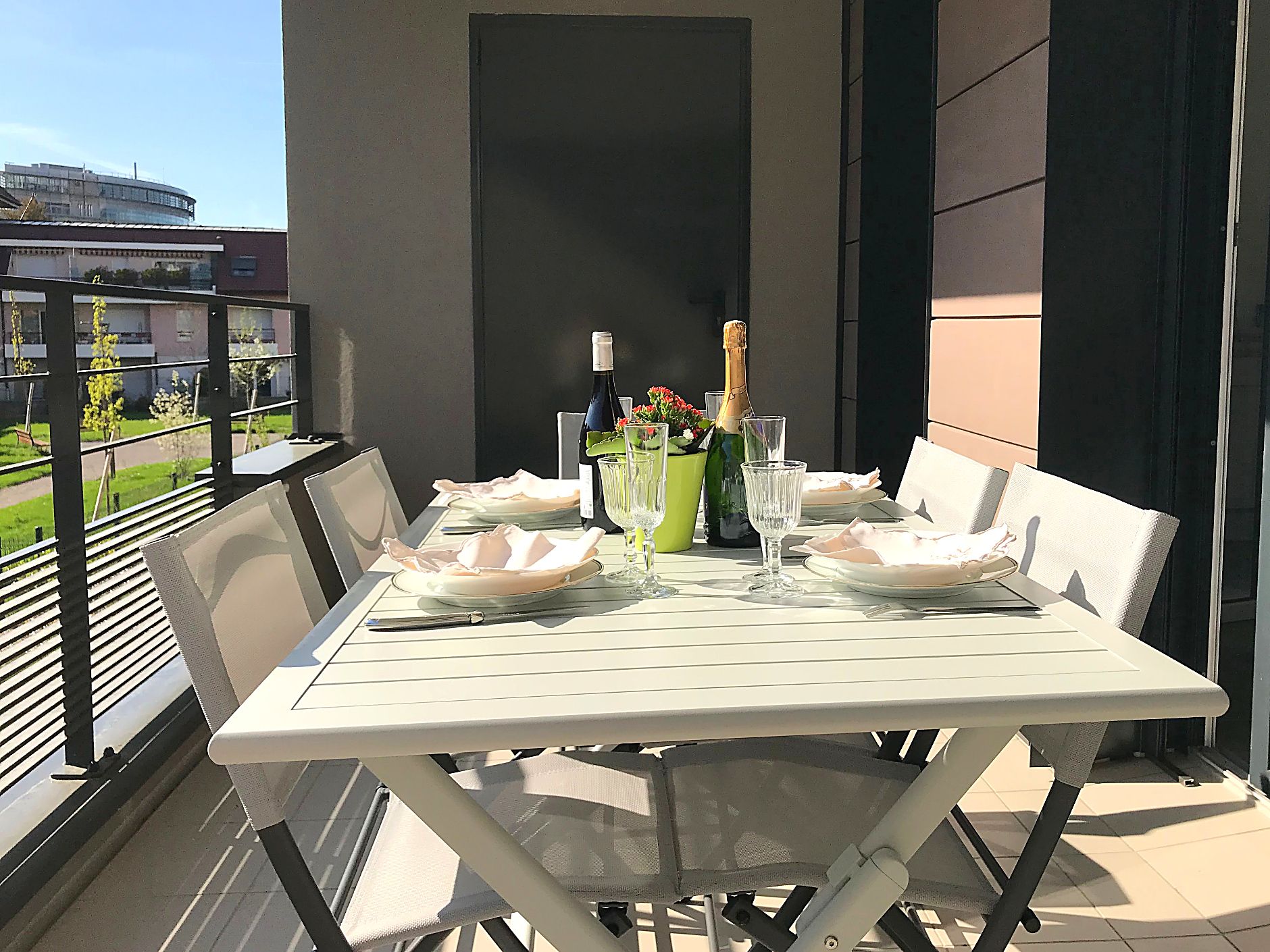 A dining table set for two with plates, cutlery, glasses, and a bottle of champagne.