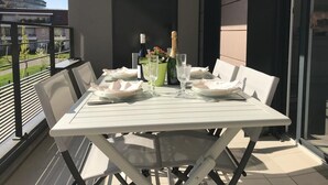 A balcony with a table set for two, featuring a bottle of champagne, glasses, and a small vase with flowers. - T3 Golden Triangle : Annecy Green *** (ANNECY)