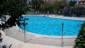 Une piscine entourée de verdure et de bâtiments.