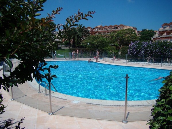 A swimming pool surrounded by greenery and buildings.