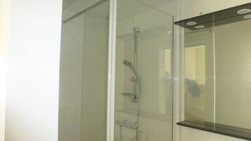 A modern bathroom with a glass-enclosed shower, a mirror, and a sink.