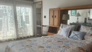 Une chambre à coucher avec un grand lit, une armoire en bois, un ventilateur de plafond et une fenêtre avec des stores.
