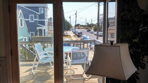 Vue depuis une pièce donnant sur une terrasse en bois, avec une table et des chaises.