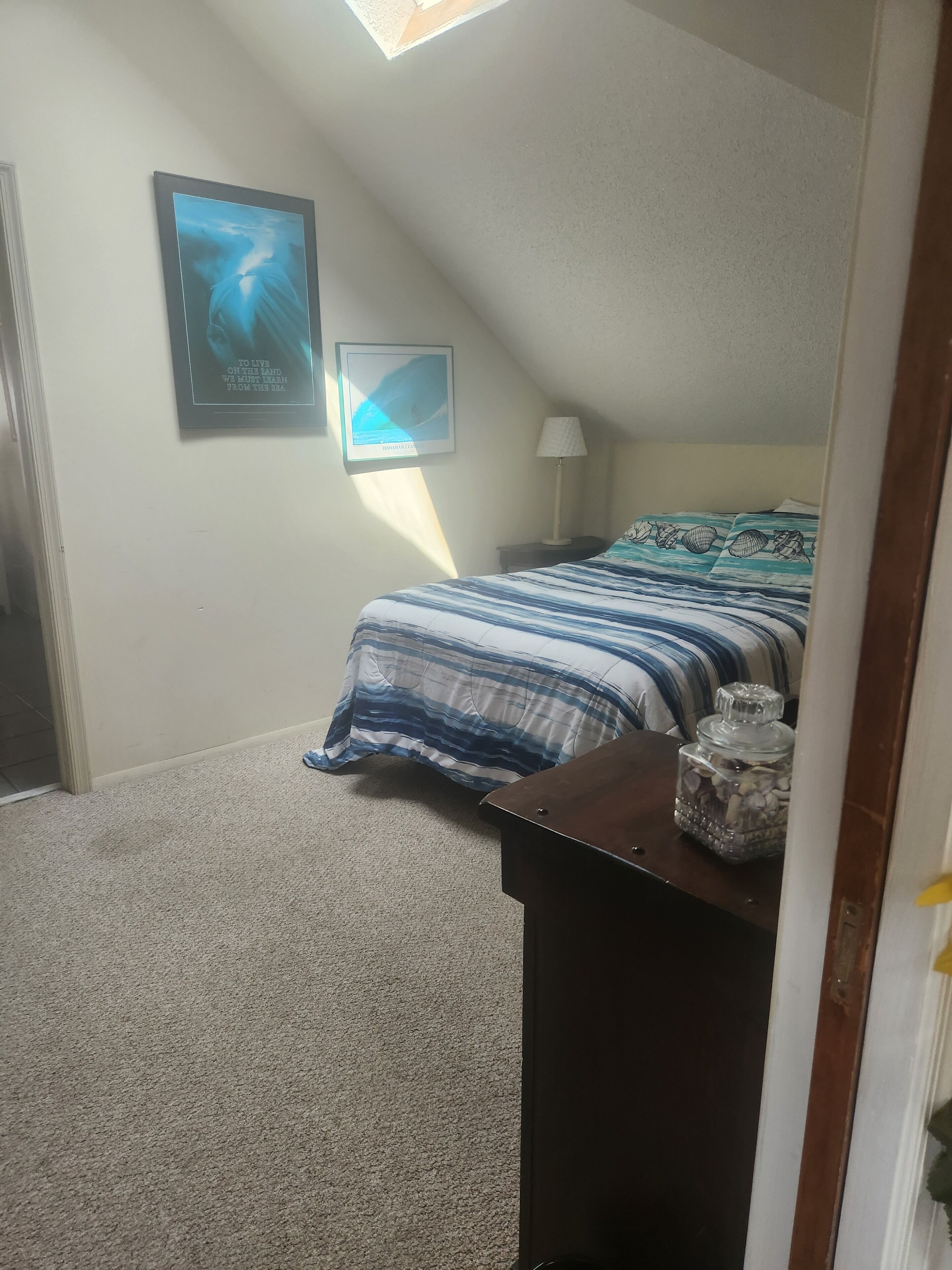 A bedroom with a bed, a nightstand, a lamp, and a framed picture on the wall.