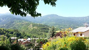 A rural landscape with a house surrounded by greenery and mountains in the background. - Guillestre ground-floor rental for 2 to 4 people, beautiful south-facing view. (Guillestre)