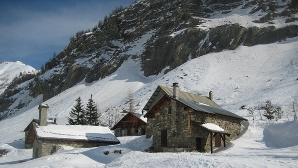 A stone cabin with a sloped roof, surrounded by snow-covered ground and a mountainous backdrop. - Guillestre ground-floor rental for 2 to 4 people, beautiful south-facing view. (Guillestre)