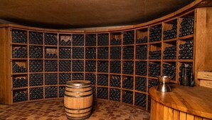 A wine cellar with wooden racks filled with wine bottles, a barrel, and a bar area. - THE ANNEX holiday home in the heart of the vineyard (Verdigny)