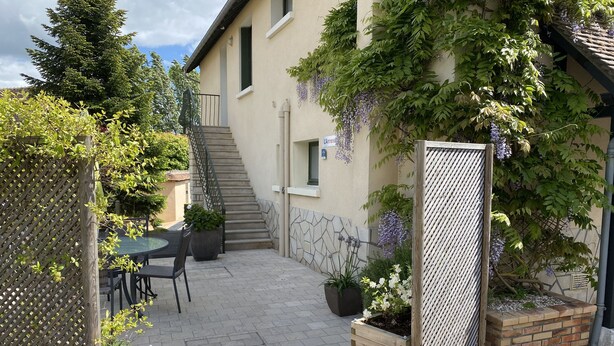 A patio area with a table and chairs, a wooden fence, and a staircase leading to an upper level. - THE ANNEX holiday home in the heart of the vineyard (Verdigny)