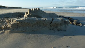A sandy beach with a large sandcastle and scattered rocks. - Typical house, completely renovated, comfortable and warm. (Plonéour-Lanvern)