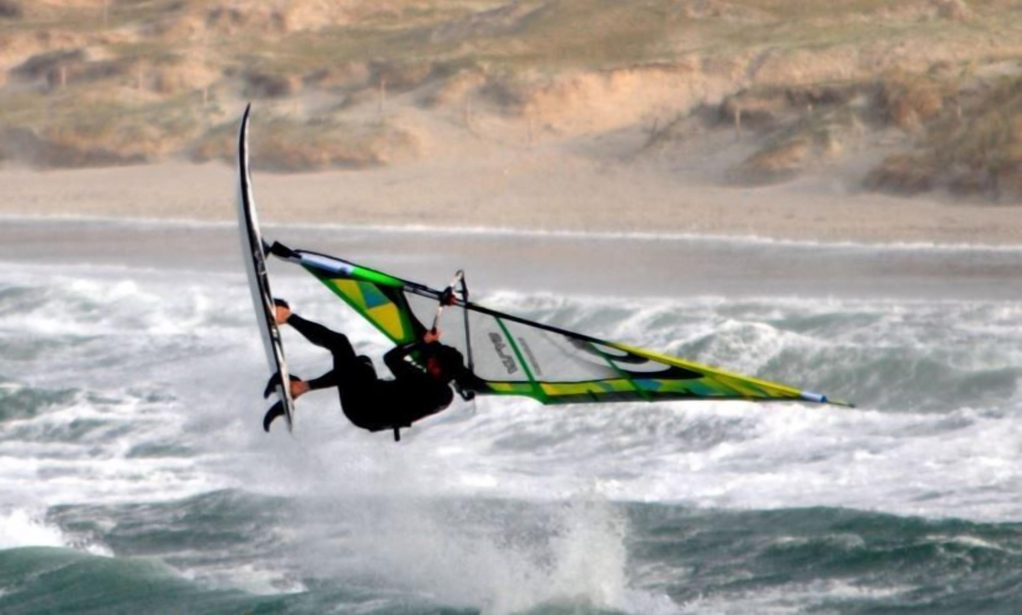 Une personne pratiquant la planche à voile dans une zone côtière où il y a des vagues.