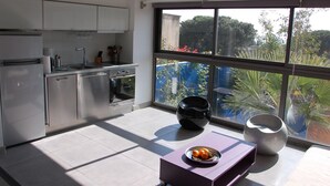 A modern kitchen with stainless steel appliances, a large window offering a view of greenery, and a purple table with a fruit bowl. - Cassis Large studio, Terrace, village and beach on foot, private parking in Provence (Cassis)