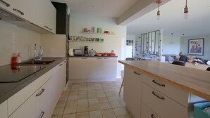 A modern kitchen with white cabinets, a black countertop, and a wooden island. There are shelves above the counter holding various kitchen items.