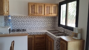 A kitchen with wooden cabinets, a tiled backsplash, a window, and a sink. - LITTLE PIECE OF HEAVEN (SOMONE)