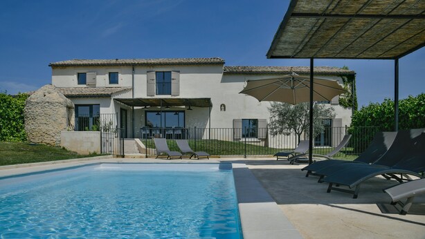 Une maison à deux étages dotée d’une piscine, d’un espace salon extérieur et d’un patio couvert.