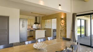 Une cuisine moderne dotée d’un îlot central, d’un coin repas avec une table et des chaises en bois, et d’un mur d’accent en pierre.