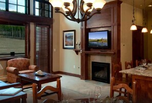 A cozy living room with a fireplace, a television, and a dining area with chairs and a table.