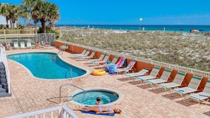 A pool area with a hot tub, lounge chairs, and a view of the beach. - Beachfront Family Condo w/ Balcony Views, Hot Tub, Pool & Great Rates (Gulf Shores)