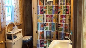 Casa de banho com sanita, lavatório e cortina de chuveiro com padrões de animais.