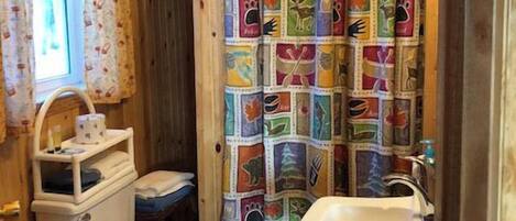 A bathroom with a toilet, sink, and shower curtain with animal prints.