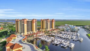 A marina with numerous boats docked, surrounded by a hotel complex with multiple high-rise buildings and a waterfront view. - Beautiful Upscale 6th floor Condo (Cape Coral)