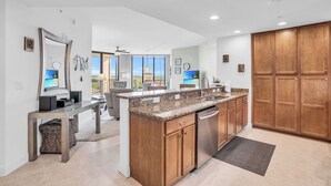 A modern kitchen with granite countertops, wooden cabinets, and a built-in dishwasher. - Beautiful Upscale 6th floor Condo (Cape Coral)