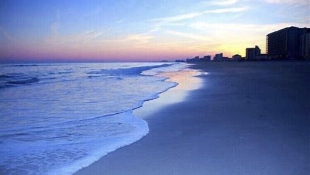 A beach with a calm sea and a city skyline in the background. - Come spend a few days by  Barefoot Landing available July 10-14 (North Myrtle Beach)
