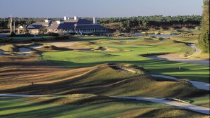 A golf course with bunkers, a clubhouse, and a flagpole. - Come spend a few days by  Barefoot Landing available July 10-14 (North Myrtle Beach)