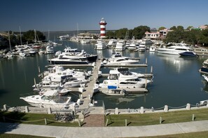 A marina with various boats docked, a lighthouse in the background, and a clear sky.