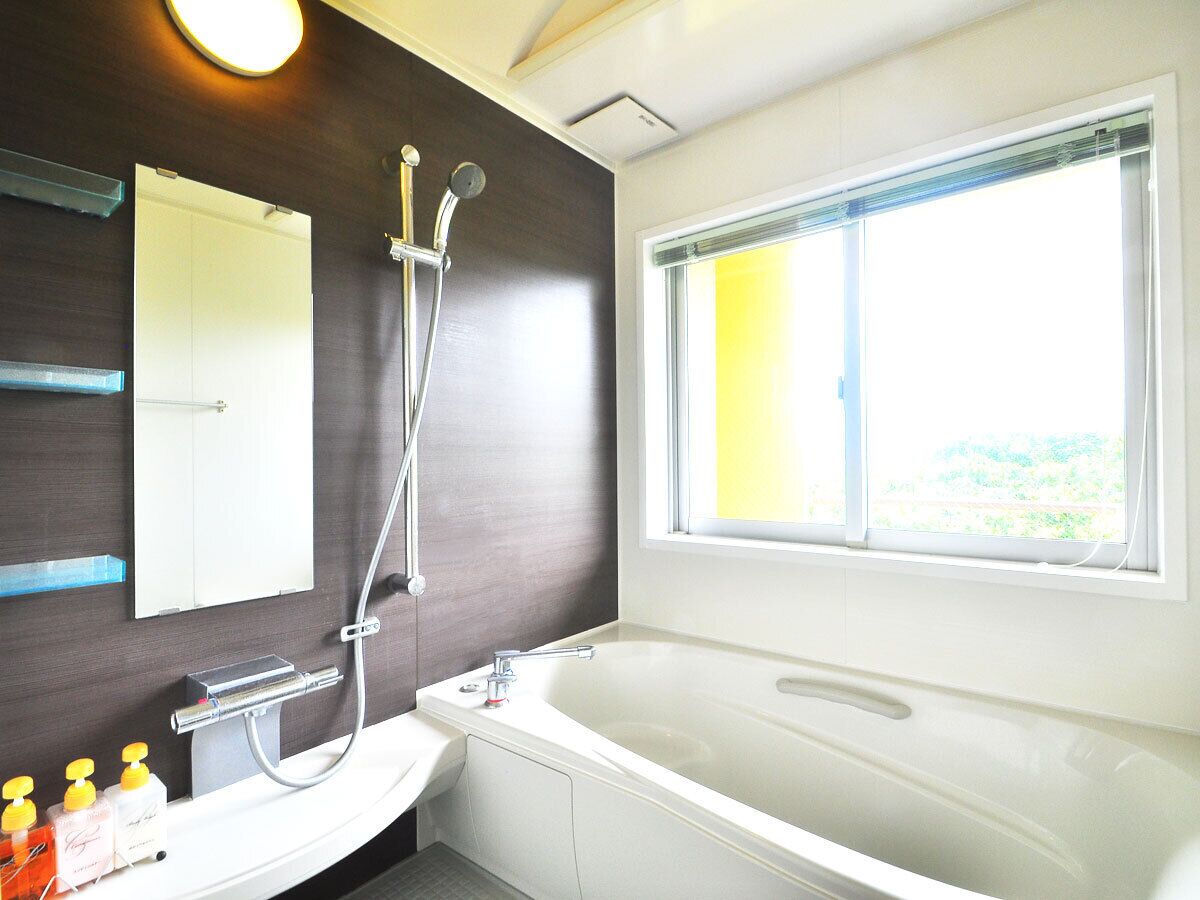 Une salle de bain moderne avec une grande baignoire, une douche, un miroir et une fenêtre.