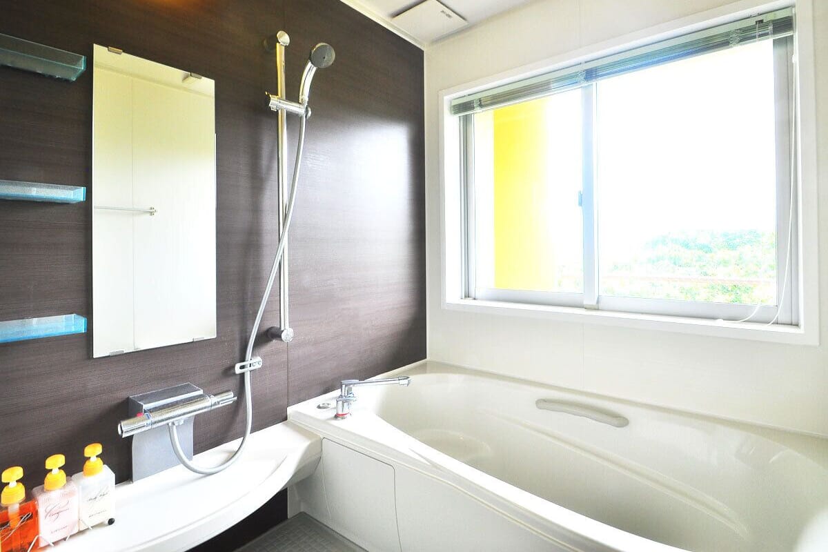 Une salle de bain moderne avec une grande baignoire, une douche, un miroir et une fenêtre.