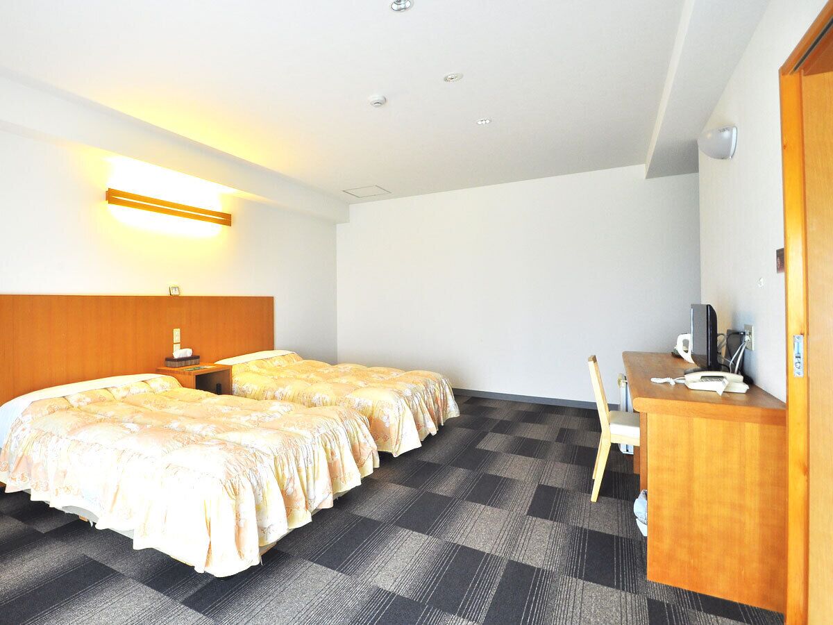 Une chambre d’hôtel avec deux lits, un bureau, une chaise et une petite table.