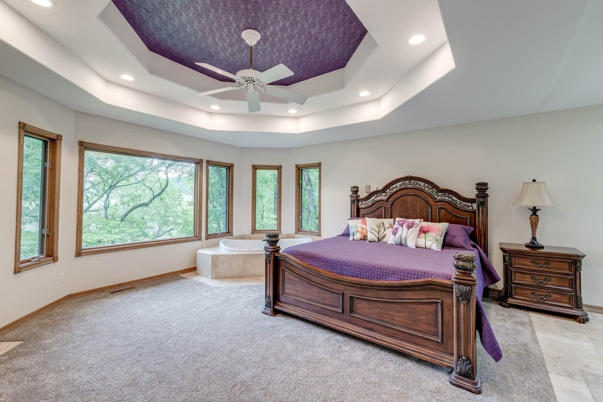 Une chambre avec un grand lit, un ventilateur de plafond et une baignoire.