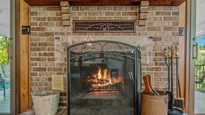 Una chimenea con una protección metálica, un letrero de seguridad contra incendios y una pared de ladrillo rústico.