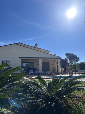A building with a pool, palm trees, and a clear sky.