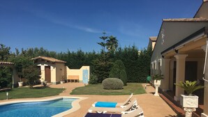 Un espace piscine doté de chaises longues et d’une piscine à l’eau d’un bleu cristallin.