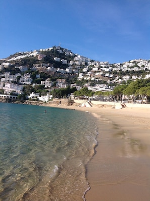 Une ville côtière avec des bâtiments construits sur une colline, une eau cristalline et une plage de sable.