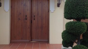 Une porte en bois à deux battants, avec un socle en pierre et un petit marchepied menant à l’entrée.