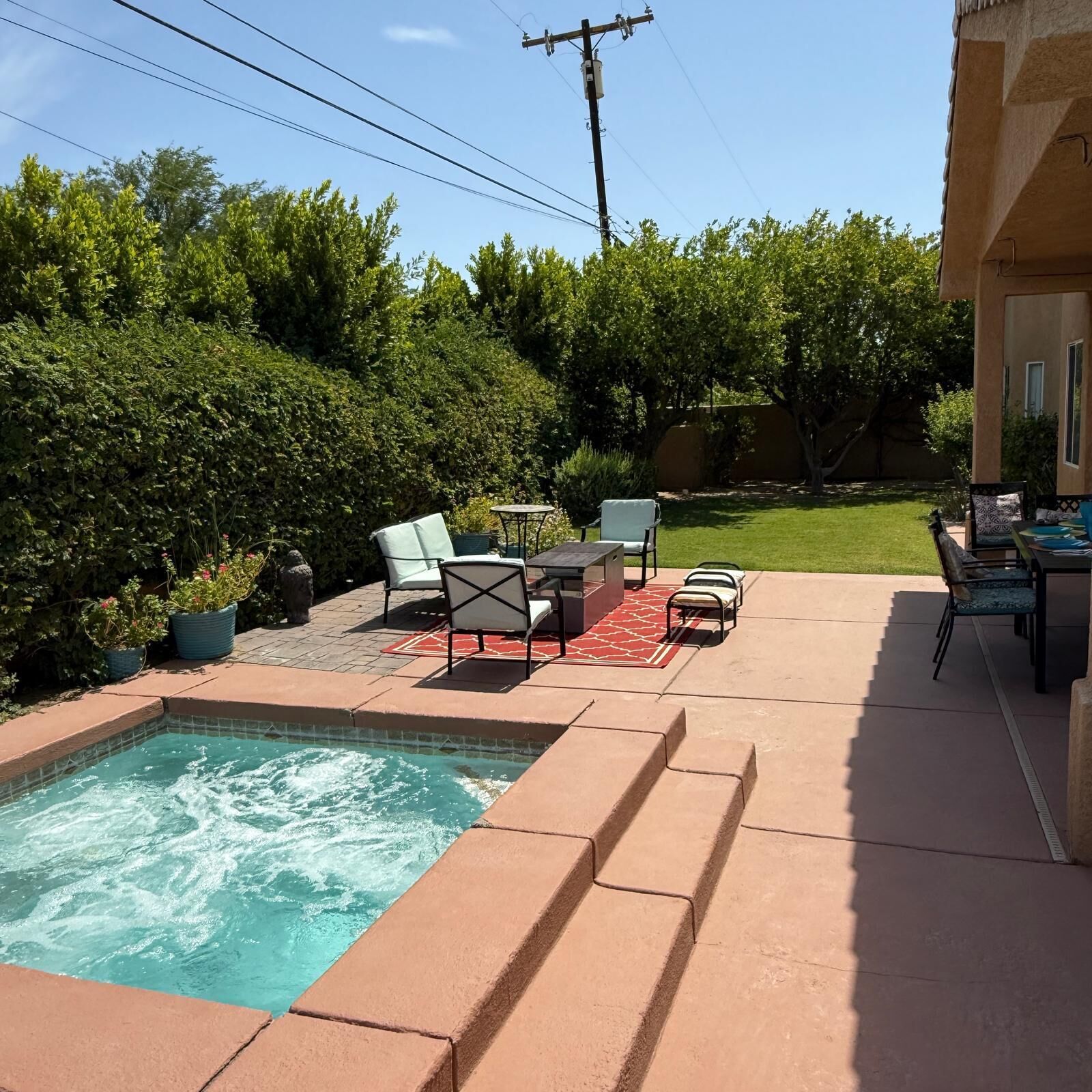 A backyard with a swimming pool, patio furniture, and a well-maintained lawn.