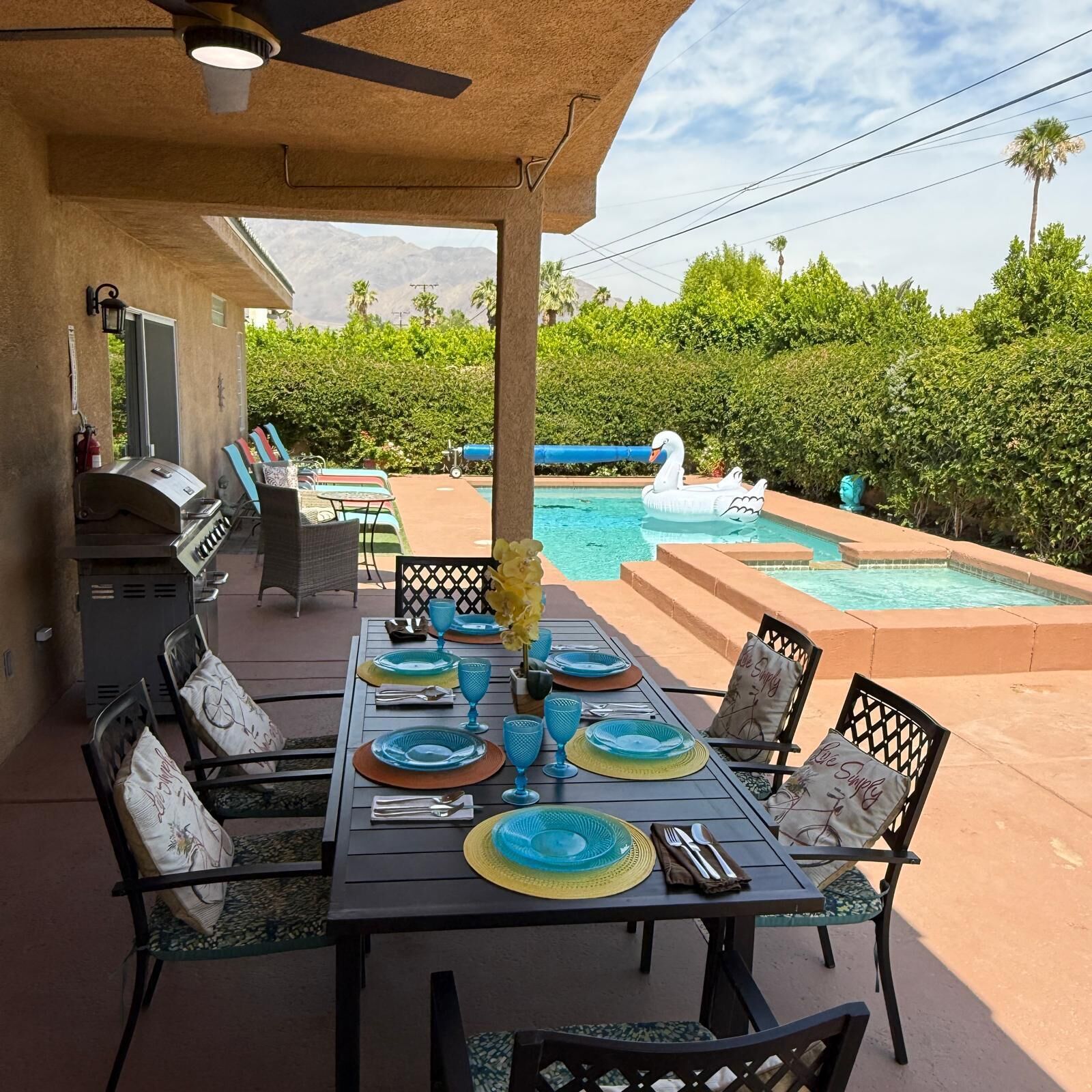 An outdoor dining area with a pool and a barbecue grill.