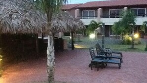 A courtyard with a palm tree, lounge chairs, and a building with a red roof.