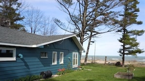 Ein blaues Haus mit einem Rasen, einem kleinen Garten und Blick auf das Meer.