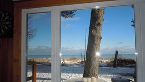 Ein Fenster mit Blick auf einen verschneiten Strand, ein Tisch mit drei Bällen und eine Dartscheibe an der Wand.