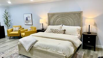 A bedroom with a large bed, two bedside tables, a chair, a floor lamp, and a wall-mounted lamp.